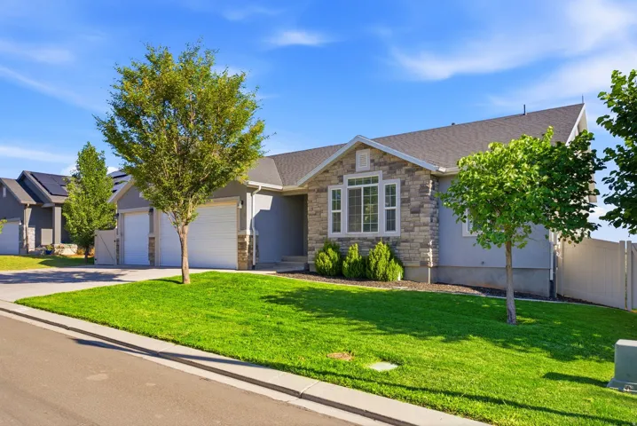 Stone and stucco exterior with multiple windows, an attached two-car garage, and a manicured lawn