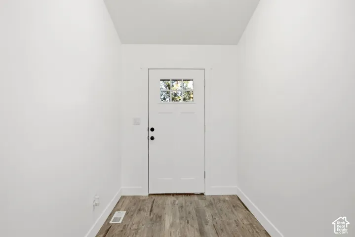 Entryway featuring a white paneled door with glass inserts, wood-finish flooring, and white trim