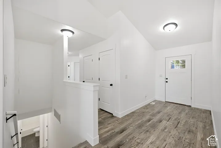 Entryway featuring wood-finish flooring, a white paneled door with glass inserts, and modern flush-mount lighting