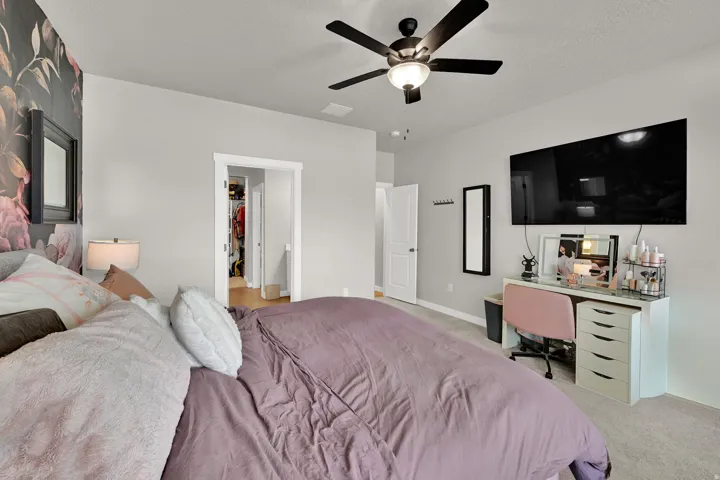 Ceiling fan with integrated lighting, wall-mounted television, light-colored carpeting, and a doorway leading to a separate area