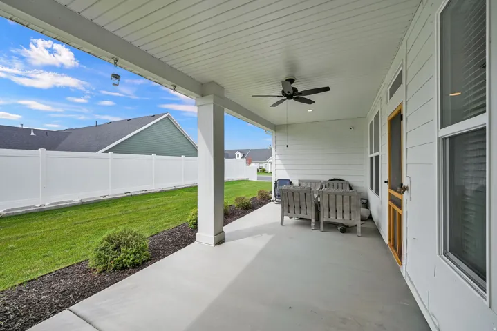 Covered patio with a ceiling fan, concrete flooring, and white vinyl siding