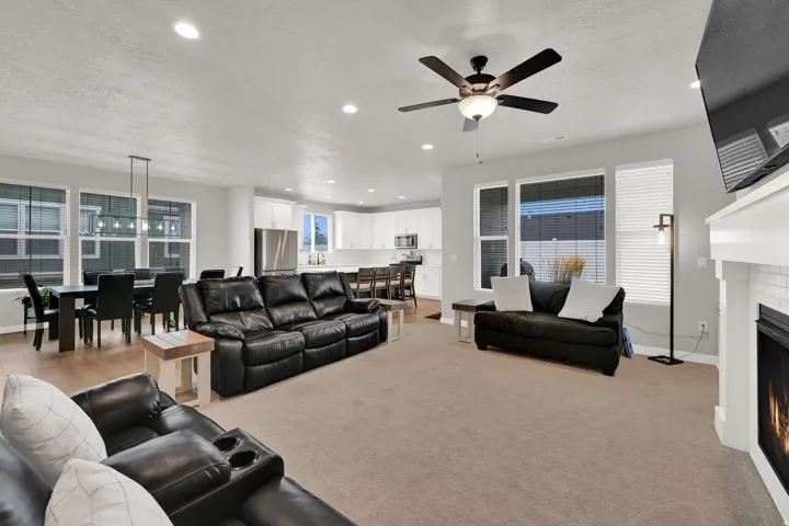Spacious living area featuring a fireplace with a white mantel, recessed lighting, and a ceiling fan