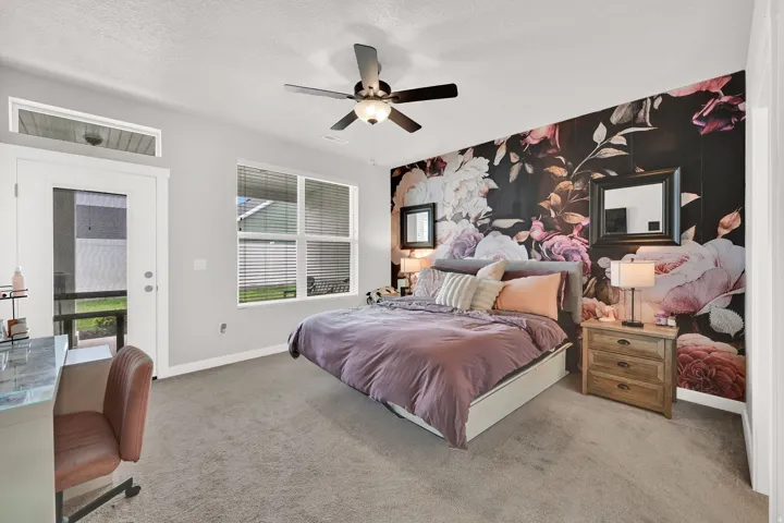 Carpeted room with a ceiling fan, a window with blinds, and a glass-paneled door with an overhead transom
