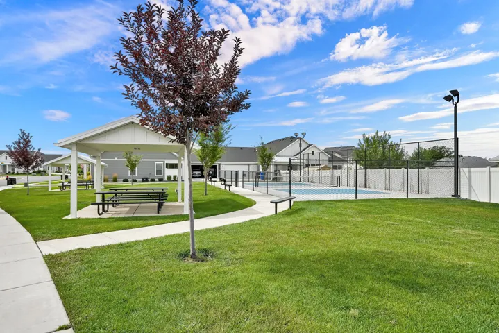 Community green space featuring a covered picnic area, paved pathways, and an outdoor swimming pool with surrounding fencing