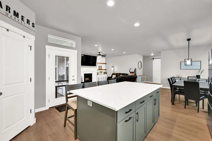 Kitchen island with a white countertop and contrasting cabinetry, wood-finish flooring, recessed lighting, and a barn door entry