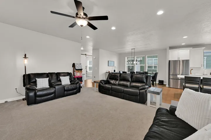 Open-concept living area with carpet flooring, recessed lighting, and a ceiling fan