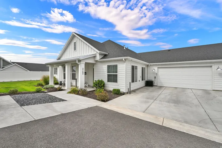 White board and batten siding, covered front porch, attached two-car garage, concrete driveway, and landscaped front yard