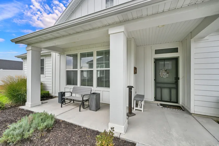 Covered front porch with substantial columns, board and batten siding, multiple pane windows, a transom window, and a dark screen door