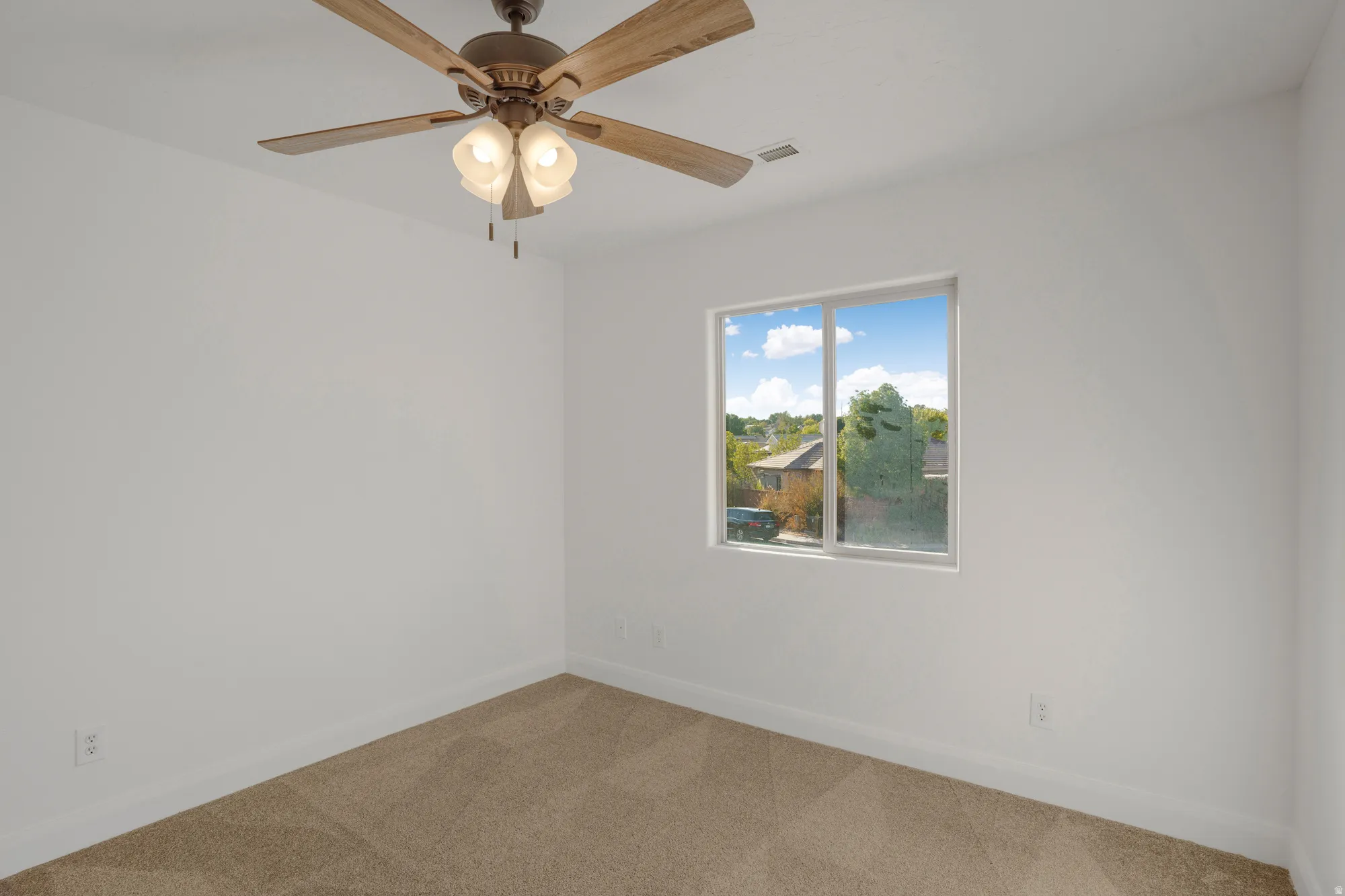 Bright room with a large window, neutral carpeting, and a ceiling fan with integrated lighting