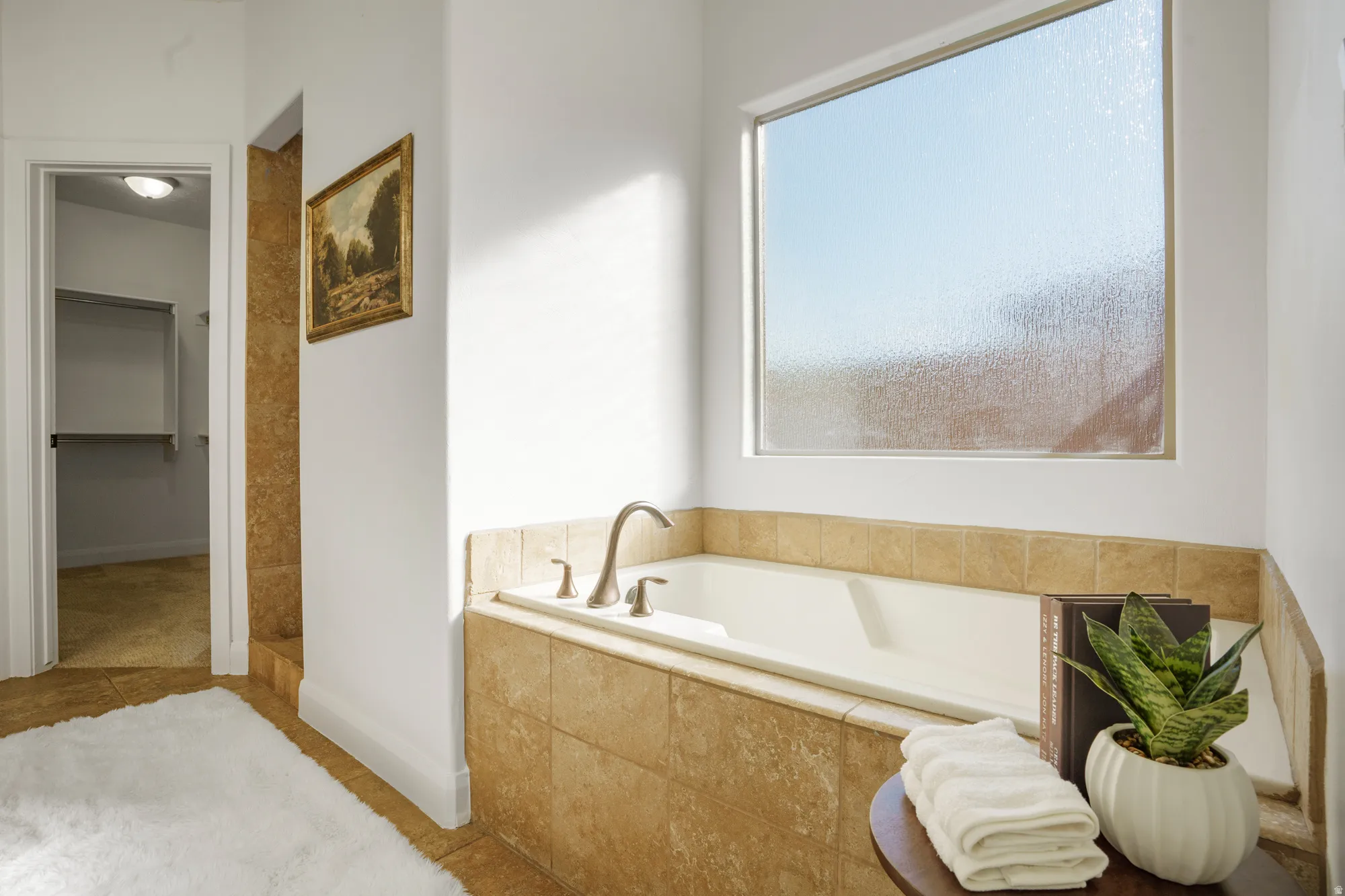 Built-in soaking tub with brushed nickel fixtures, surrounded by neutral-toned tile