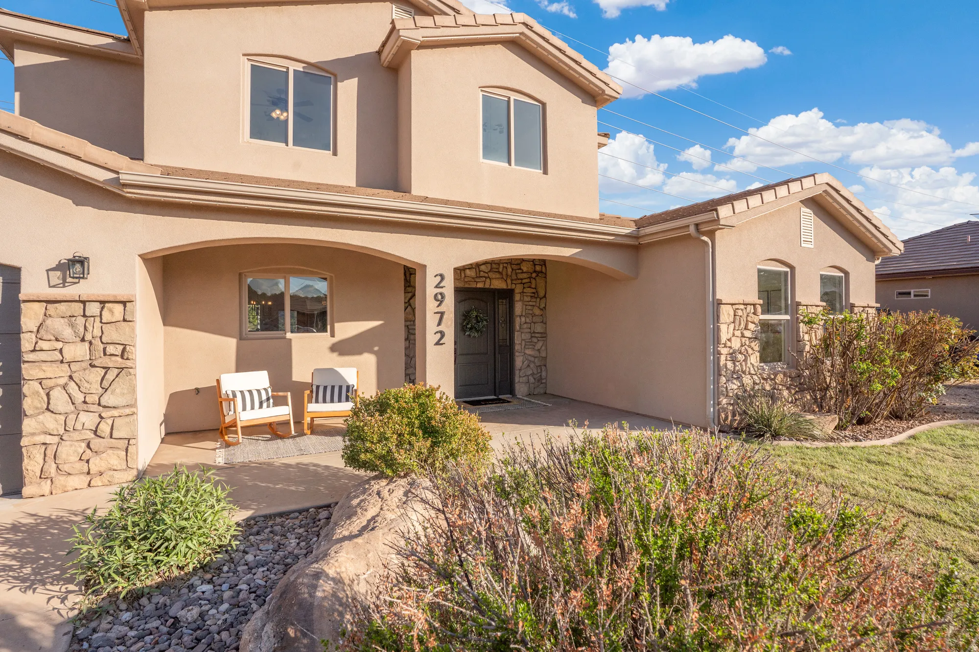 Stucco exterior with stone accents, arched entryway, and integrated garage