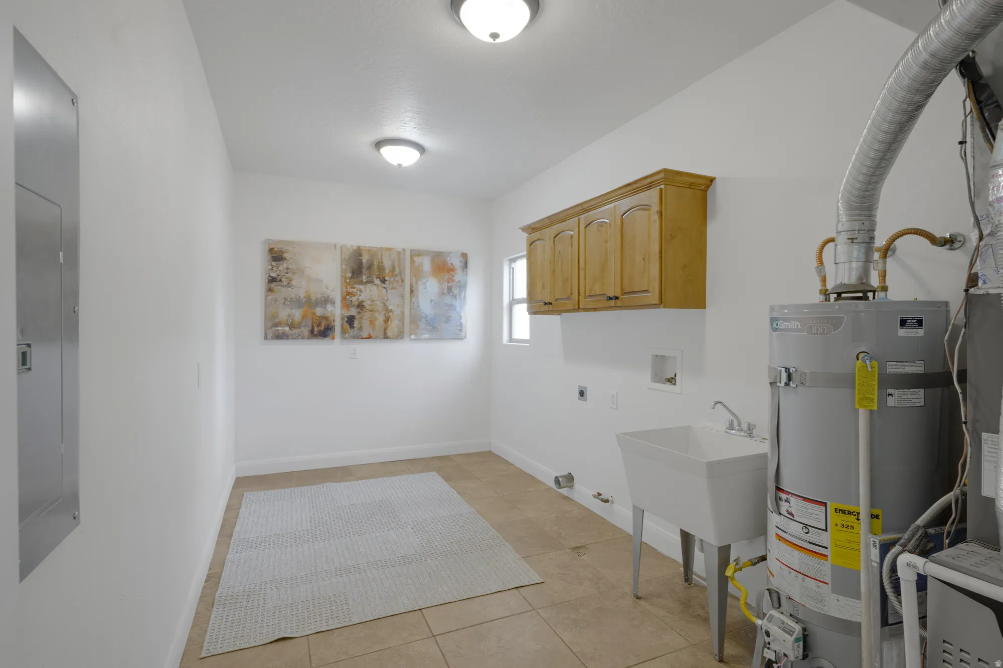 Utility room with tile flooring, built-in cabinetry, flush mount lighting, and a utility sink