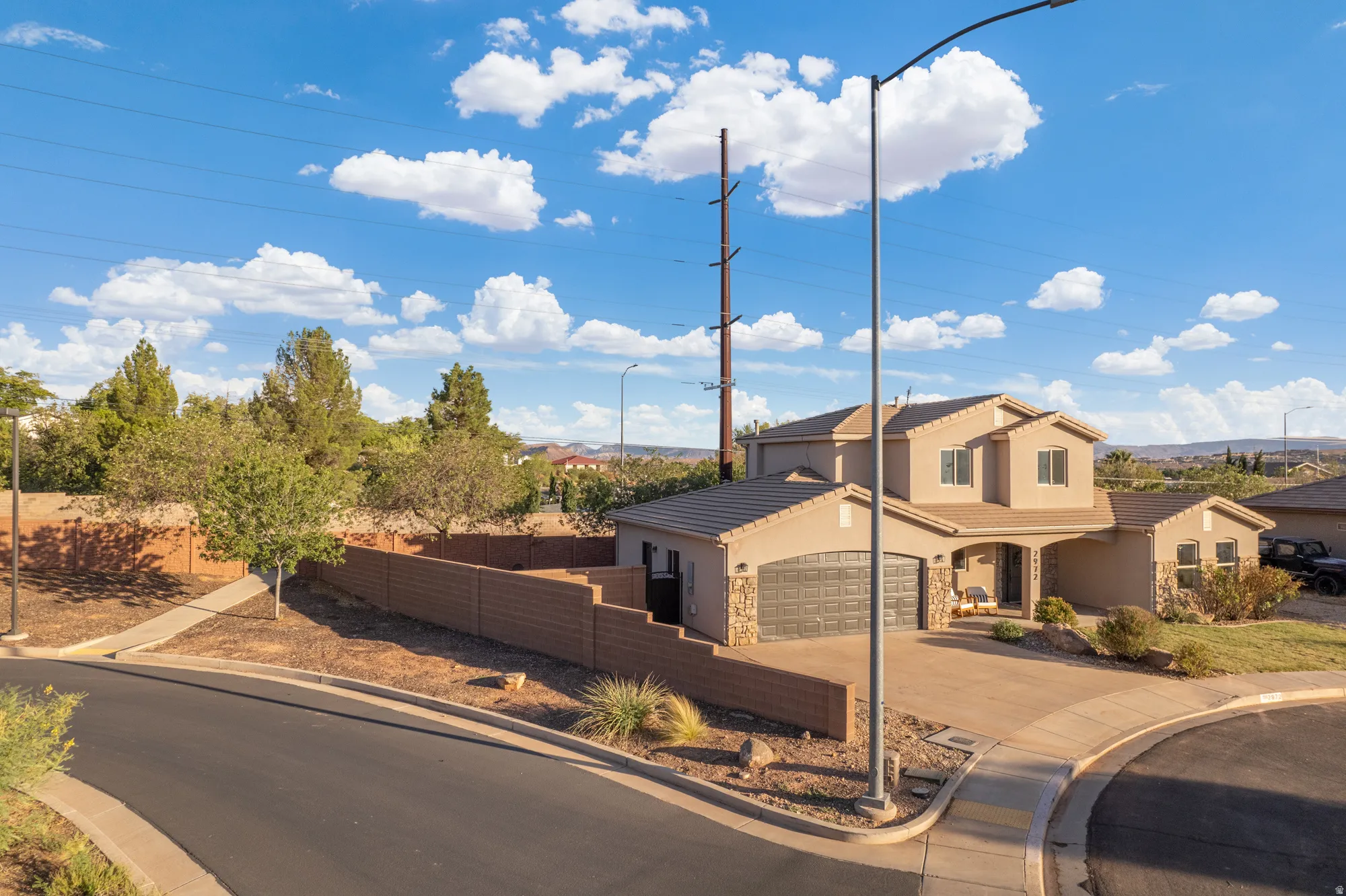 Two-story stucco exterior with stone accents, a two-car garage, and a covered entry
