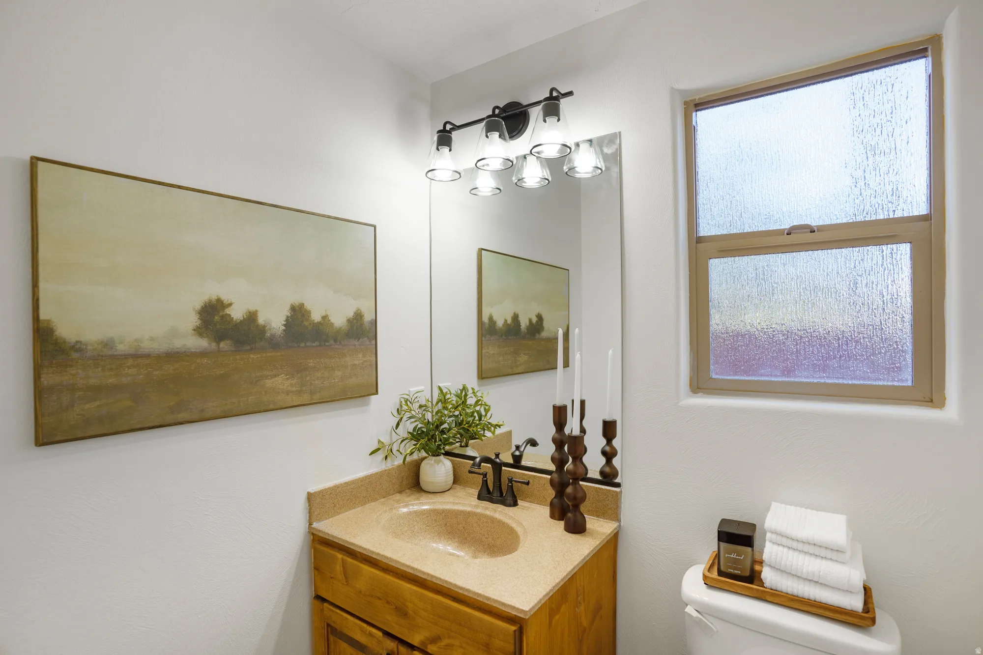 Vanity with integrated sink and stone-finish countertop, wood-finish cabinetry, and overhead lighting fixture