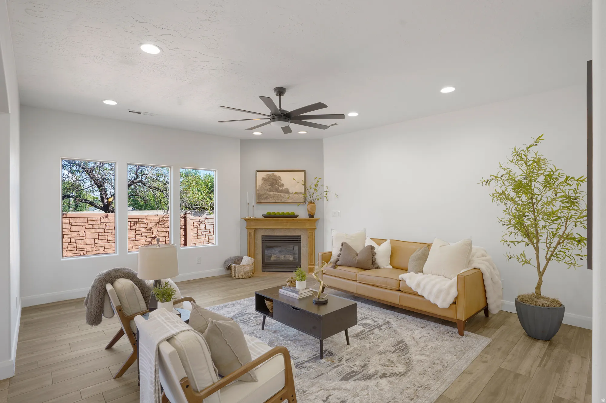 Recessed ceiling lighting, a ceiling fan, and light wood-finish flooring