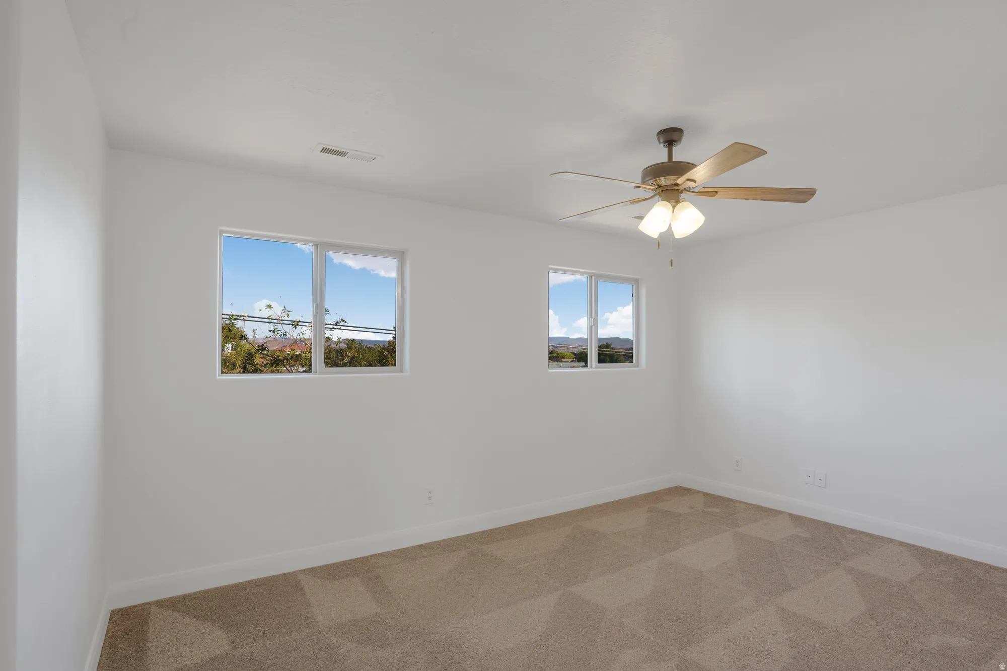 Neutral wall finishes, dual windows, and ceiling fan with integrated lighting