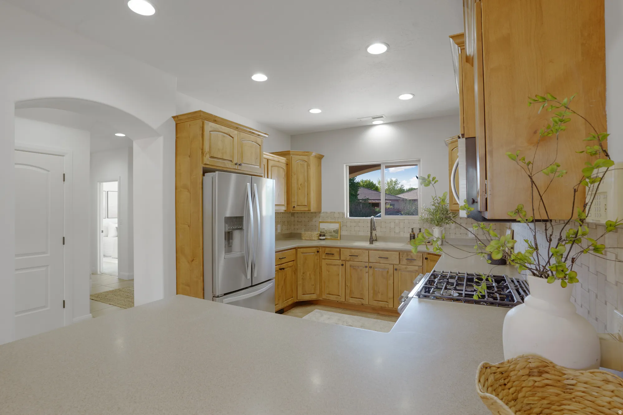 Kitchen featuring light wood-finish cabinetry, stainless steel appliances, a gas cooktop, and light-toned countertops