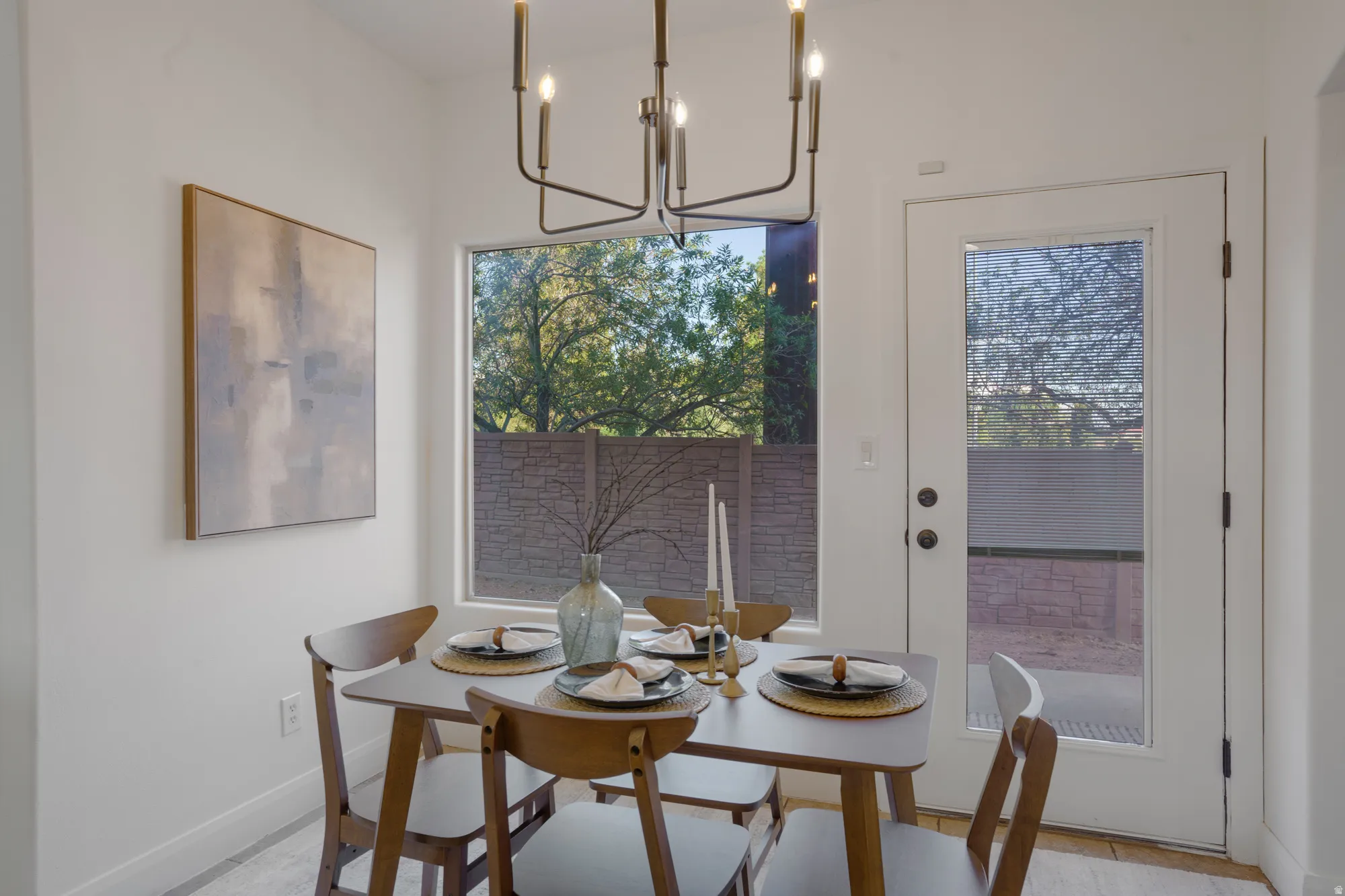 Well-lit dining area featuring a contemporary chandelier, large picture window, and a glass-paneled exterior door