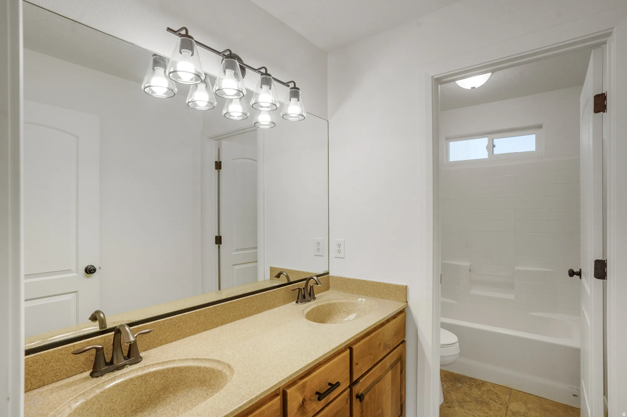 Dual vanity with integrated sinks, wood-finish cabinetry, and a full-width mirror