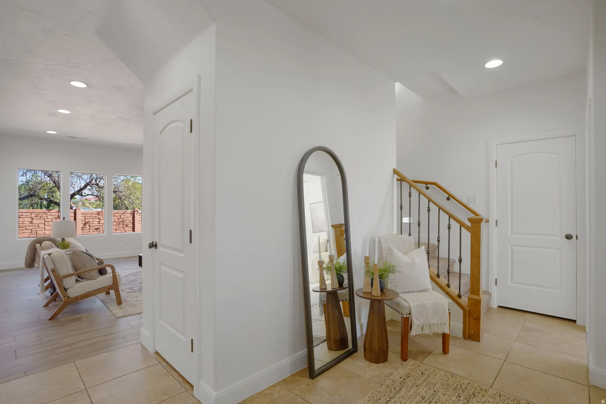Neutral wall finishes, recessed lighting, tile flooring, wood-finish staircase with wrought iron balusters, and multiple windows