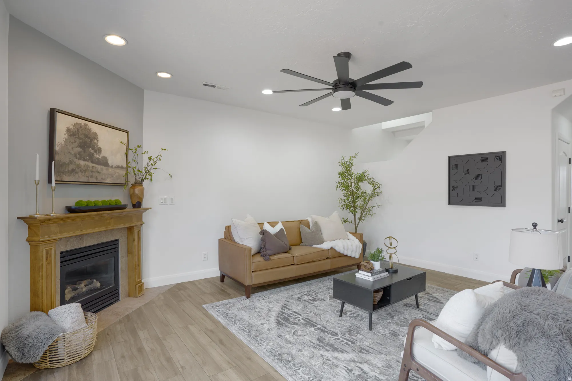 Living area featuring wood-finish flooring, a corner fireplace with a wood mantel, recessed lighting, and a ceiling fan