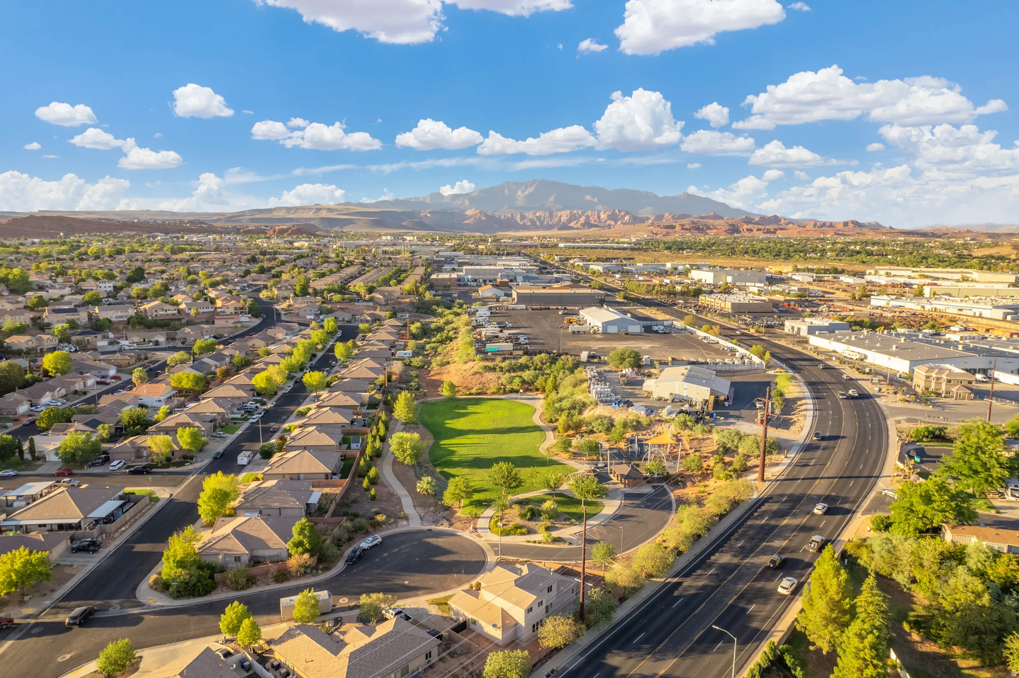 Residential neighborhood with tree-lined streets, adjacent to a commercial corridor, featuring a central green space, and distant mountains