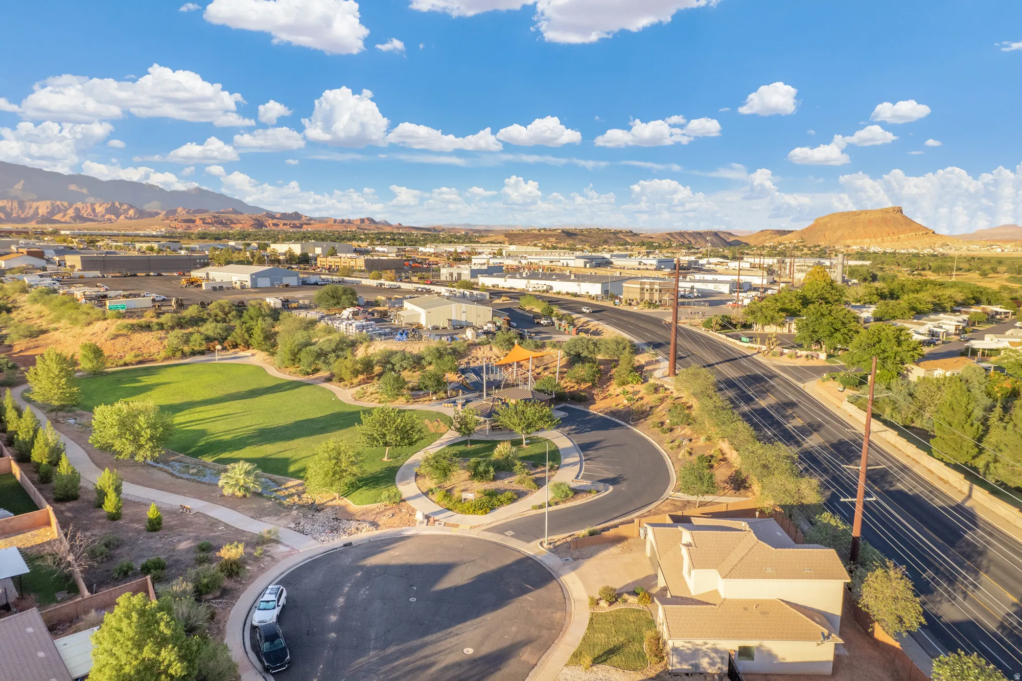 Expansive residential area with a prominent green space, surrounding desert landscaping, and a distant mountainous backdrop