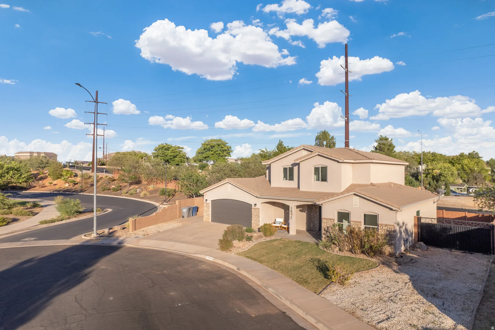 Two-story stucco and stone-fronted residence featuring an integrated garage, a covered entry, and a paved driveway