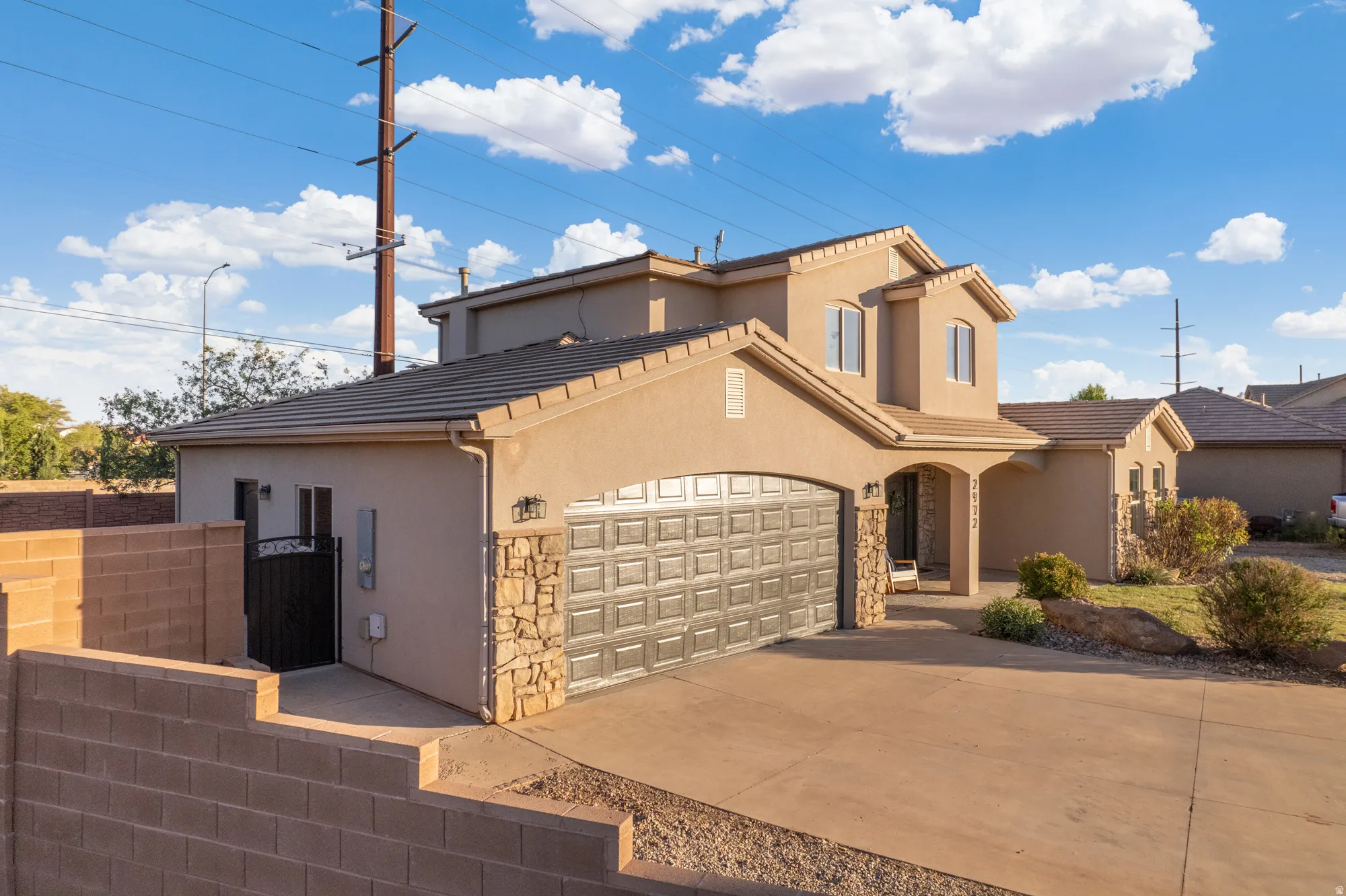 Stucco exterior with stone accents, a tiled roof, an arched entryway, and an attached garage with a paneled door