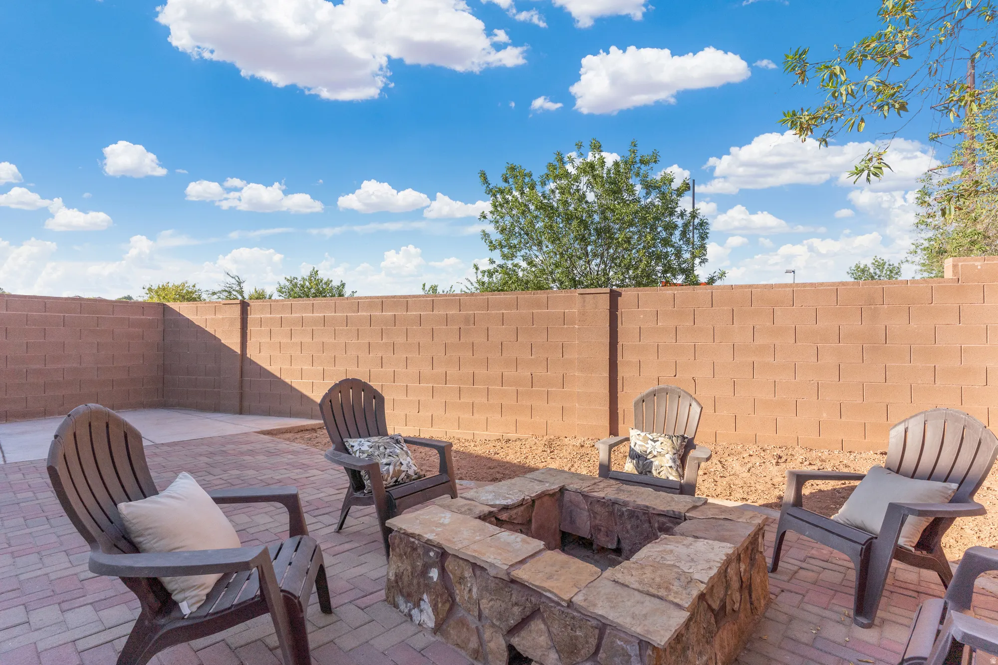 Expansive paver patio featuring a built-in stone fire pit and a block perimeter wall