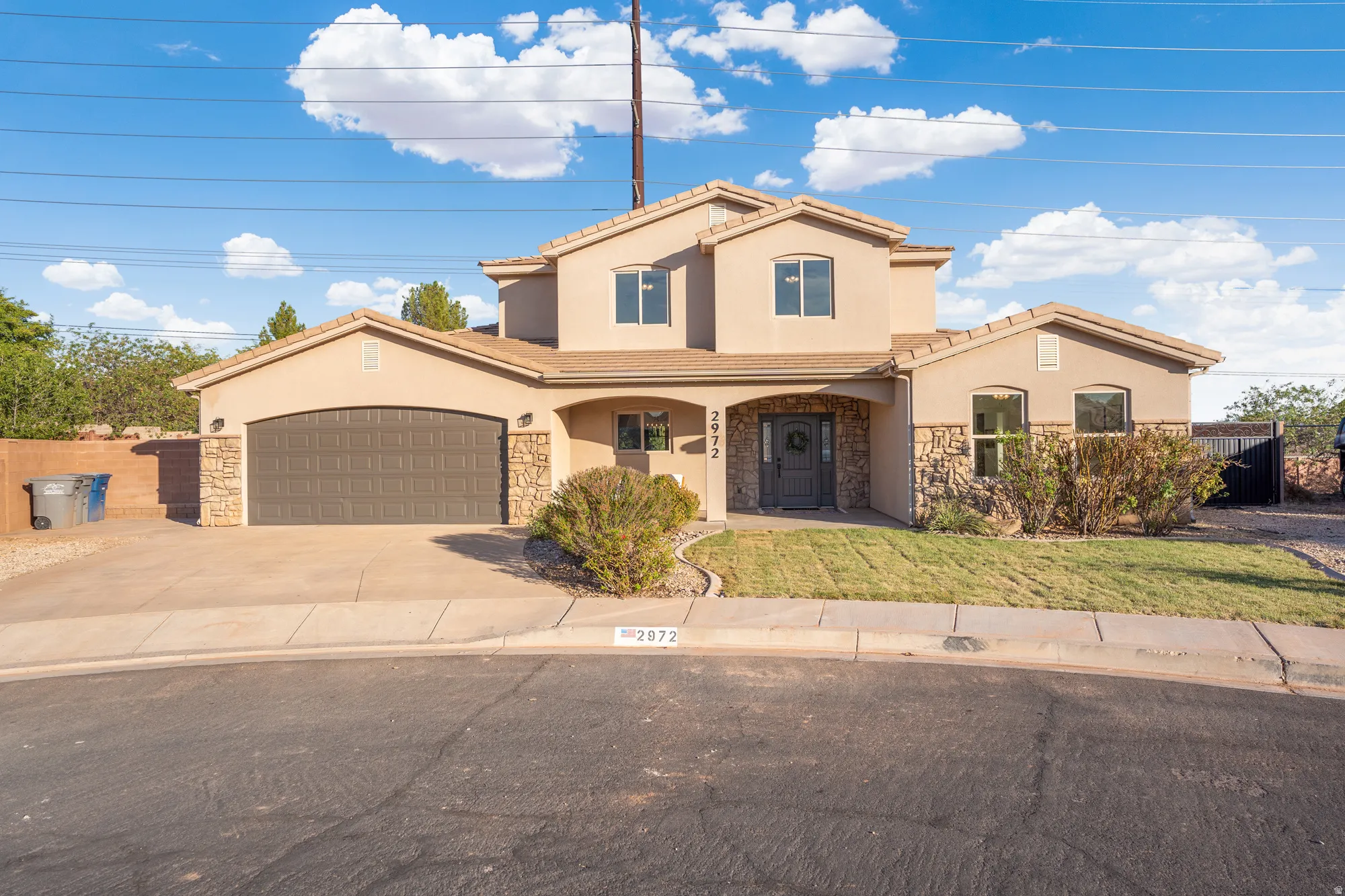 Two-story stucco exterior with stone accents, arched entry, arched garage door, and a concrete driveway