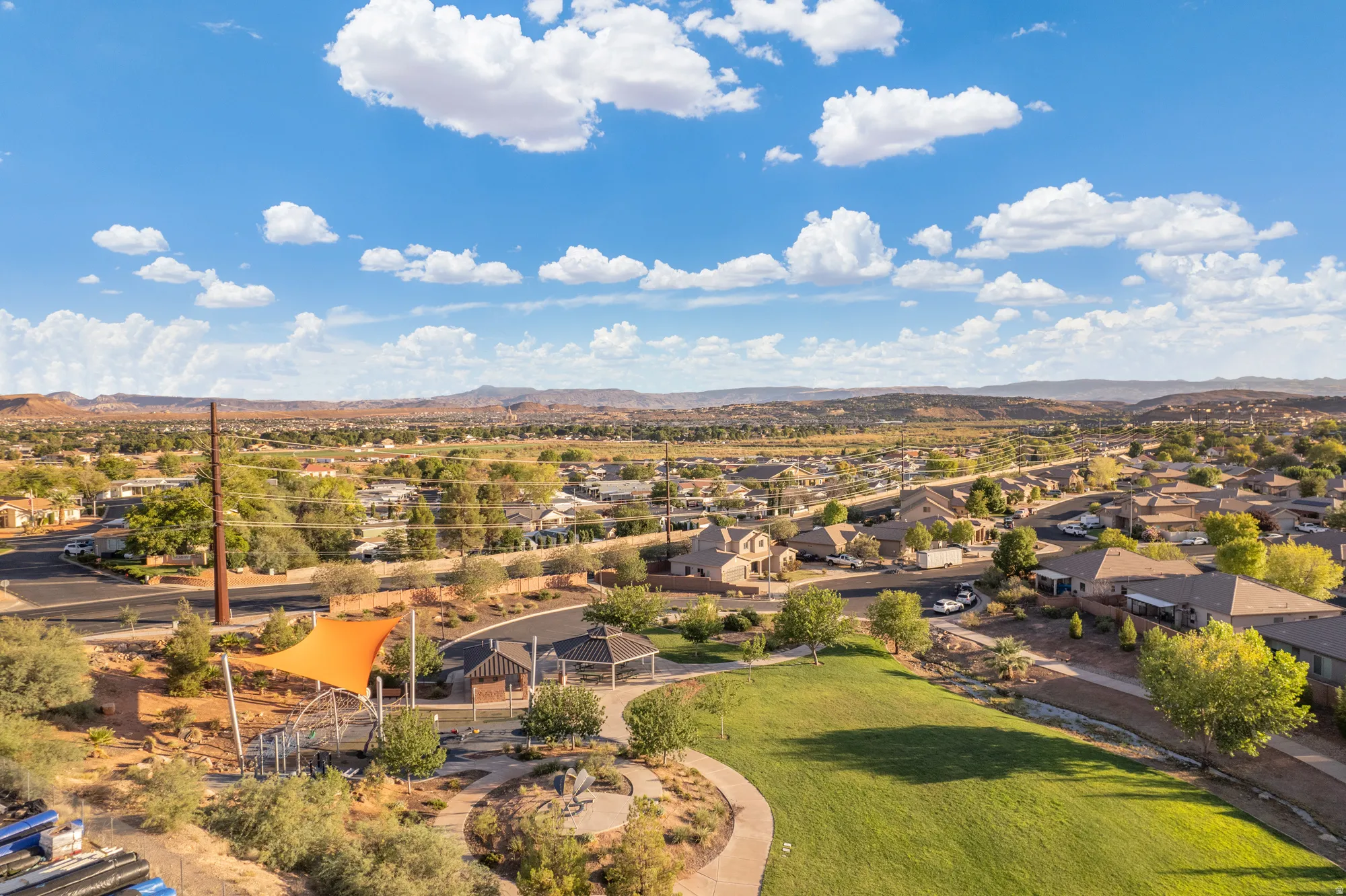 Community greenspace with a shaded play structure, open lawn, and paved walking paths