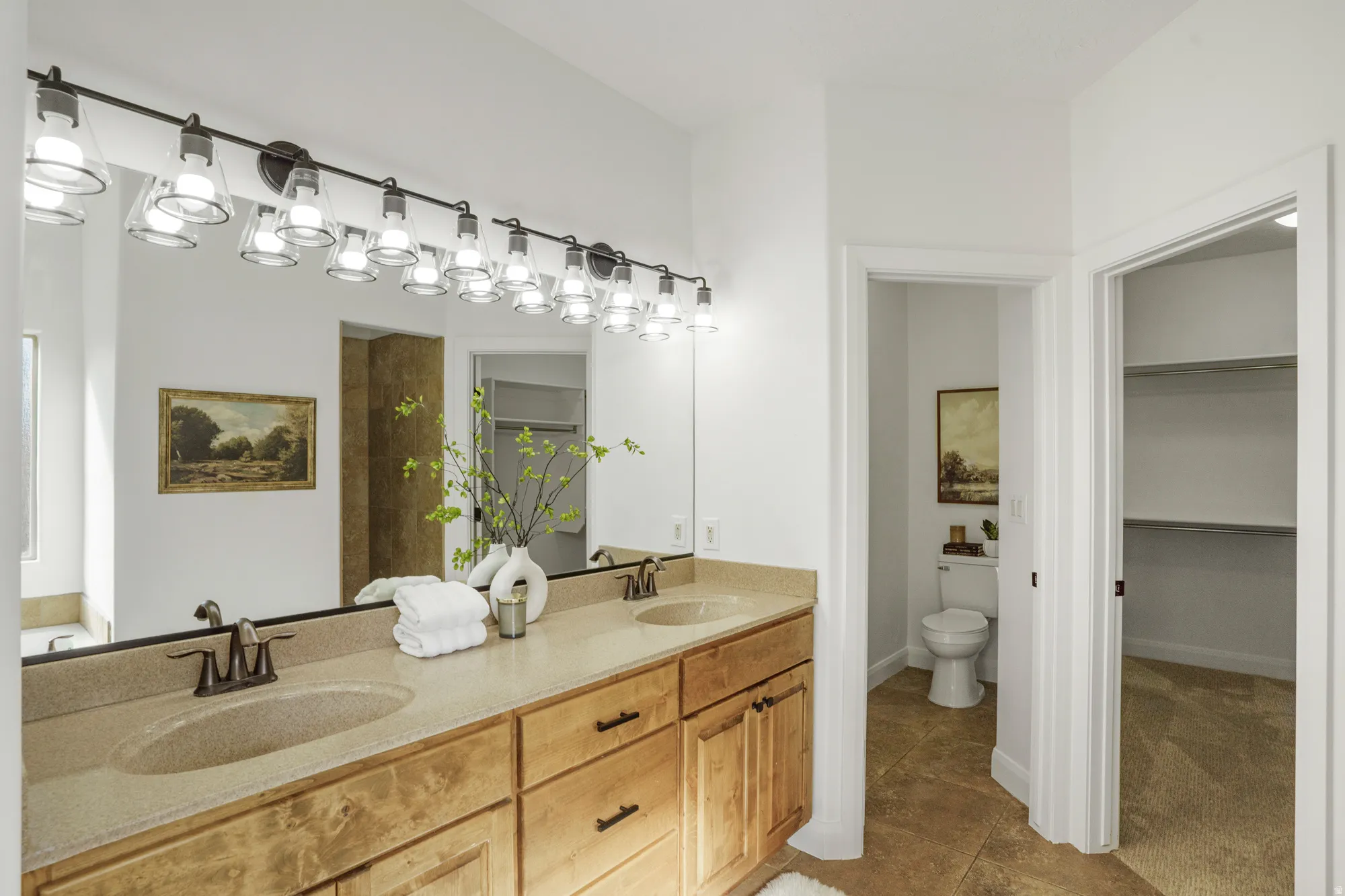 Dual vanity with integrated sinks, wood-finish cabinetry, and brushed bronze fixtures