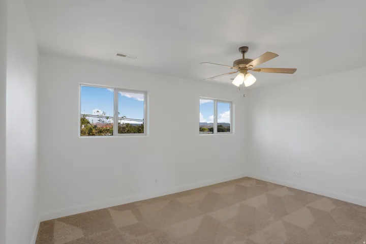Neutral wall finishes, dual windows, and ceiling fan with integrated lighting