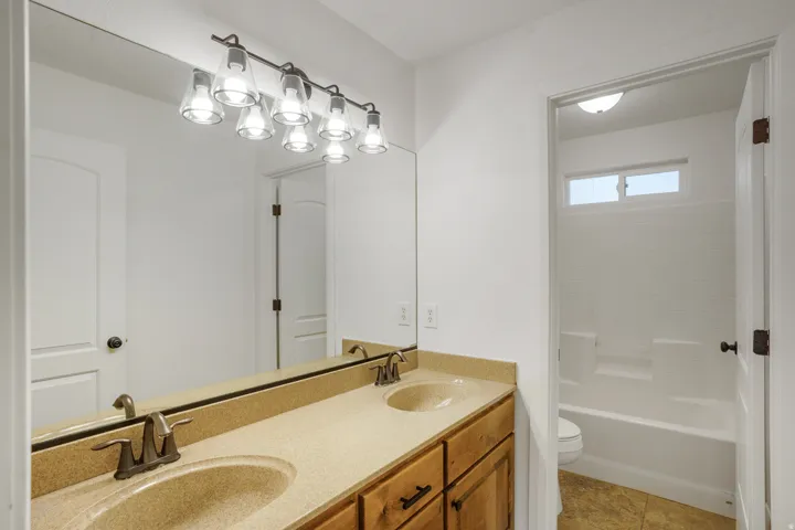 Dual vanity with integrated sinks, wood-finish cabinetry, and a full-width mirror