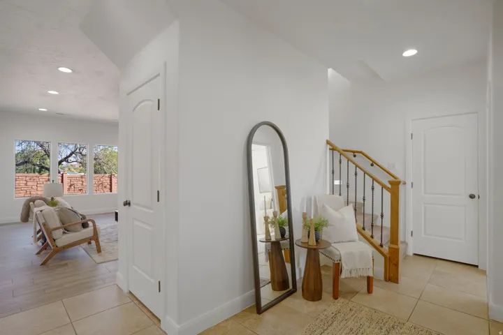 Neutral wall finishes, recessed lighting, tile flooring, wood-finish staircase with wrought iron balusters, and multiple windows
