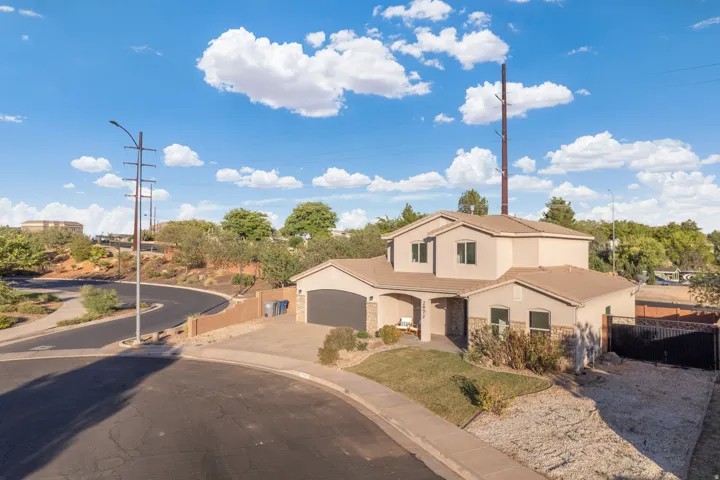 Two-story stucco and stone-fronted residence featuring an integrated garage, a covered entry, and a paved driveway