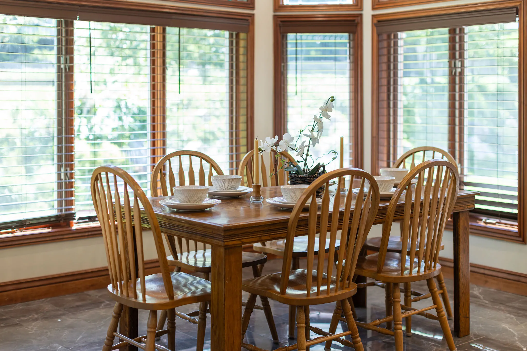 Bay window with wood-finish blinds, wood-trimmed windows, and dark tile flooring