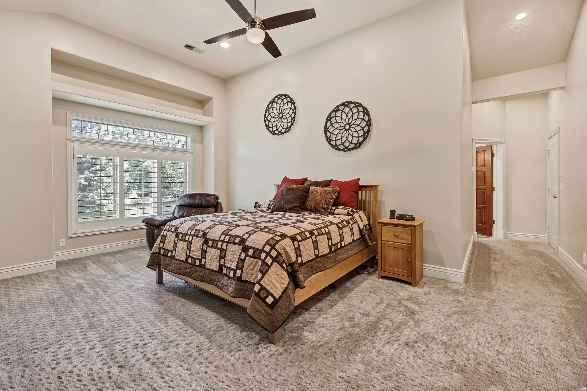 Recessed window alcove with plantation shutters, ceiling fan, carpeted flooring, and a built-in recessed niche