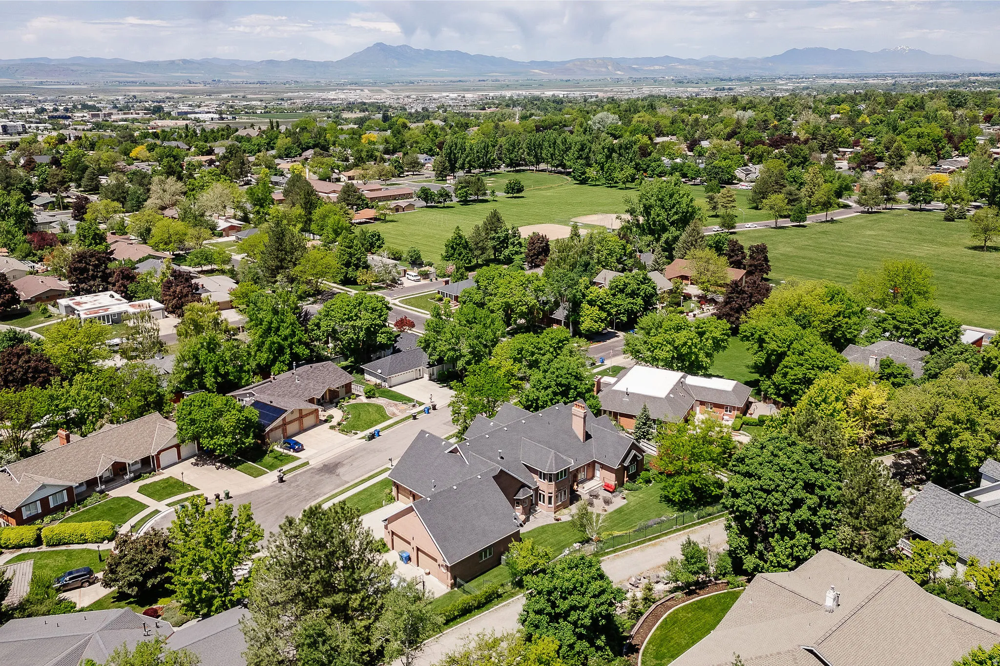 Expansive neighborhood with mature trees, green spaces, and mountain scenery