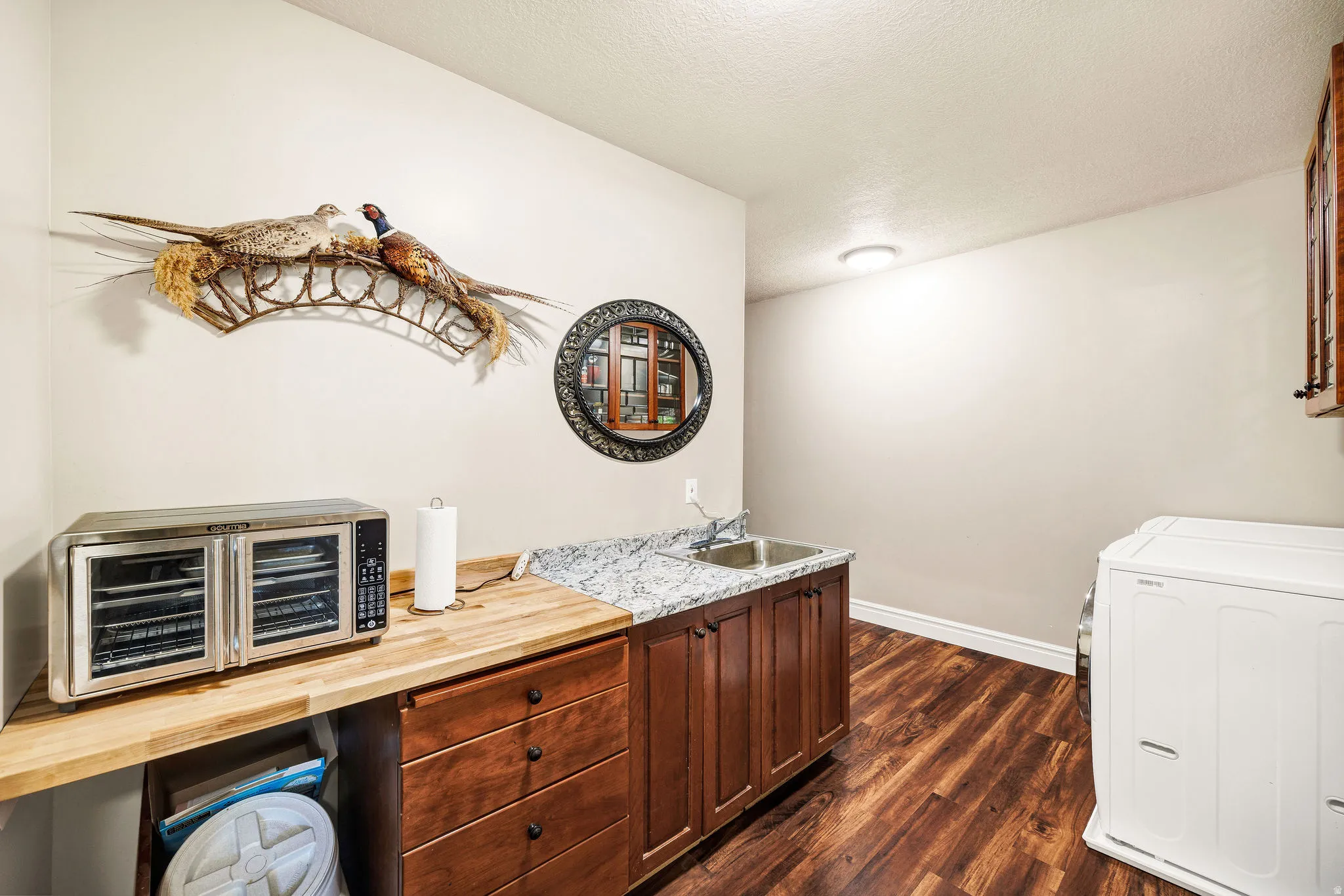 Wood-finish flooring, built-in cabinetry, granite-patterned countertop, utility sink, and recessed ceiling lighting
