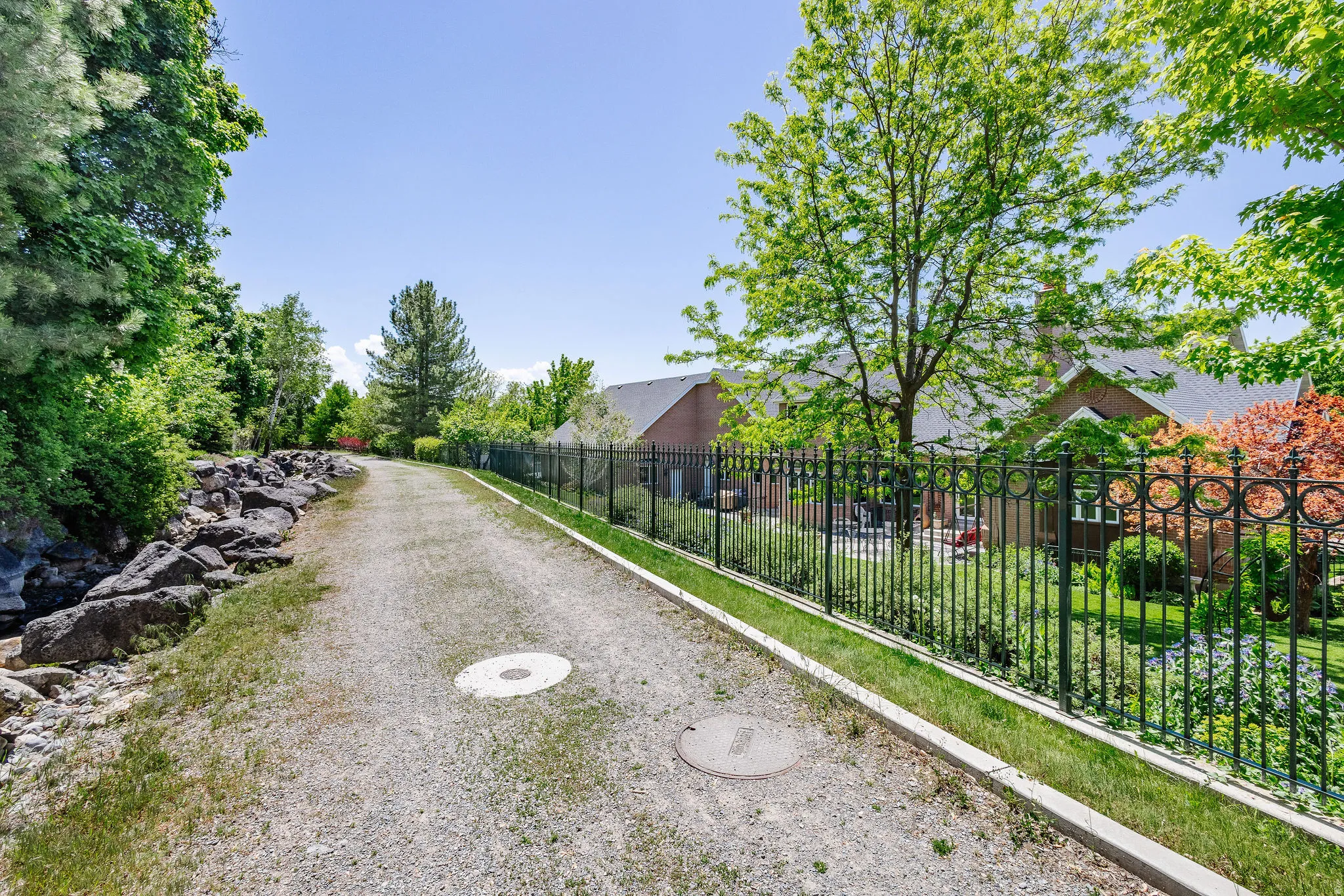 Gravel pathway bordered by a rock retention wall and mature trees