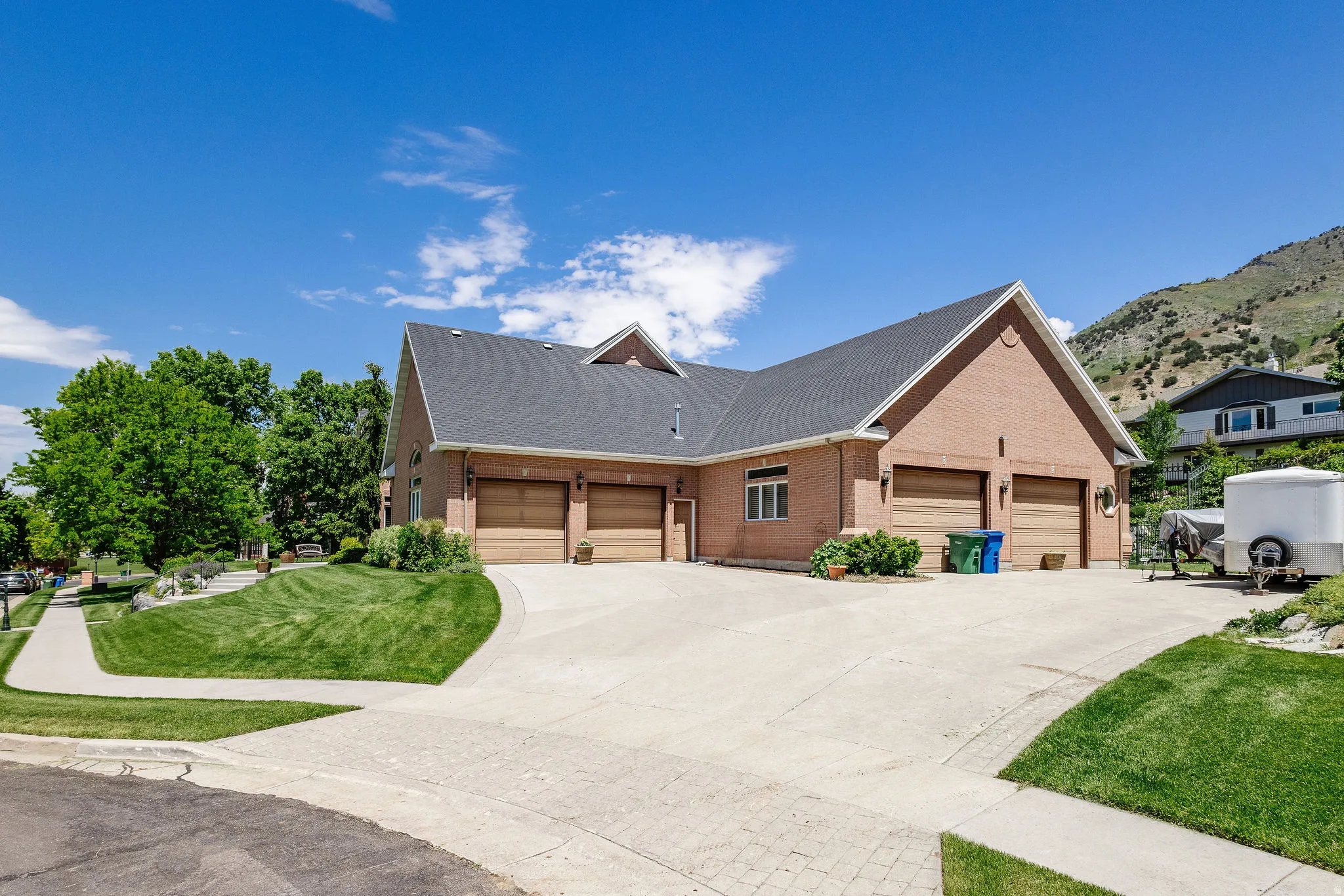 Brick exterior with a dark-pitched roof, multiple garage doors, and a concrete driveway