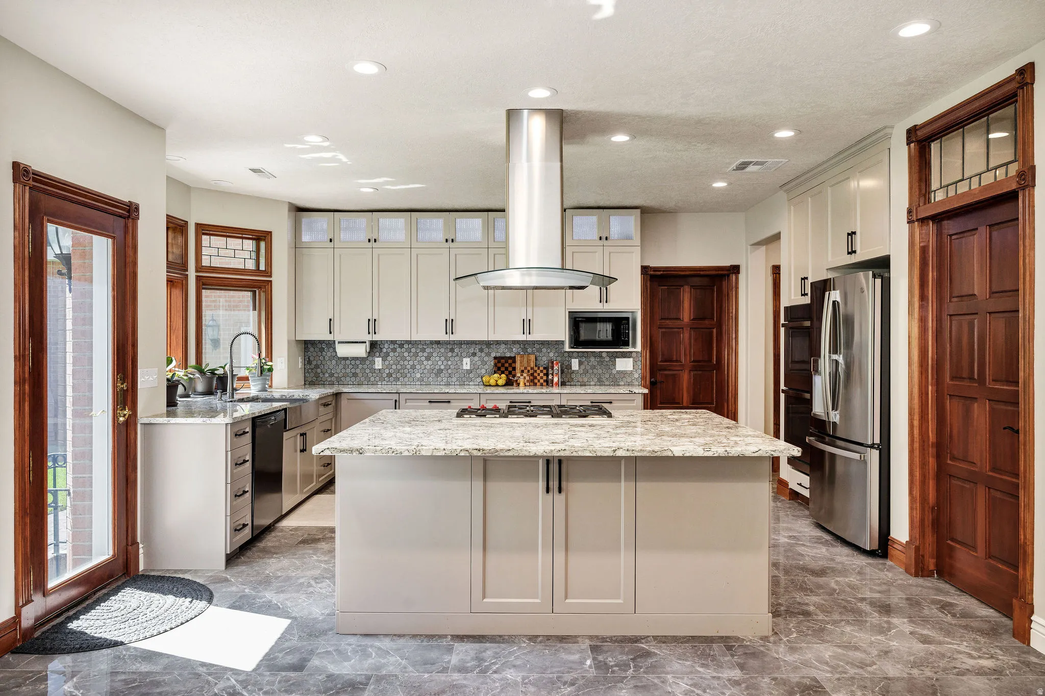 Kitchen featuring a central island with stone countertop, stainless steel appliances, light-toned cabinetry, and dark wood-paneled doors
