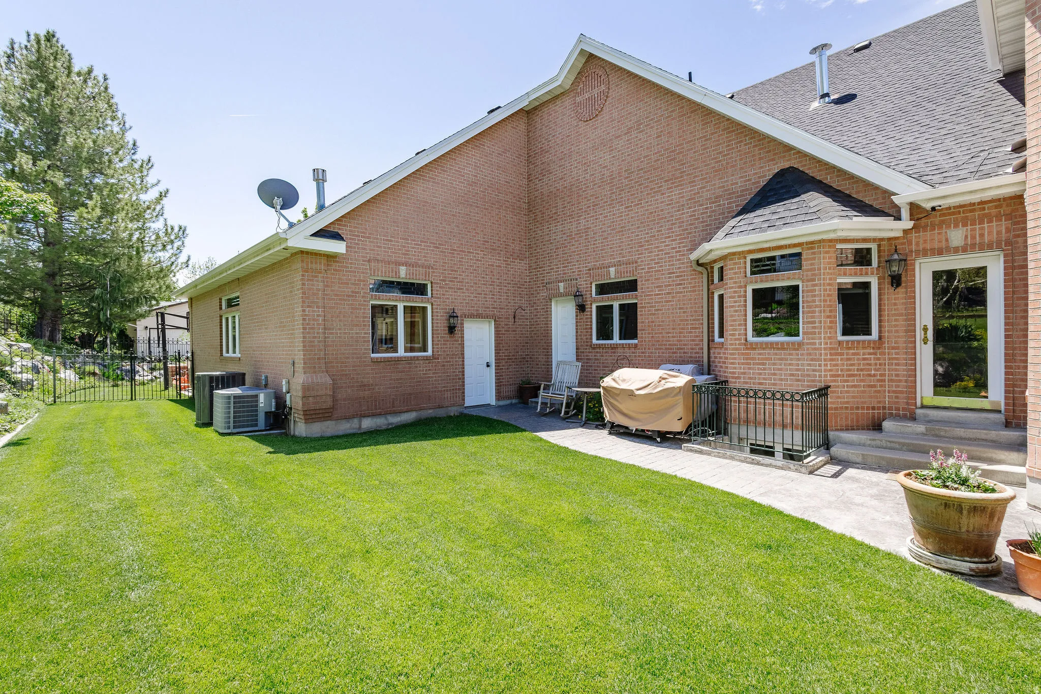 Expansive lawn area, brick exterior, bay window, exterior door, and paved patio
