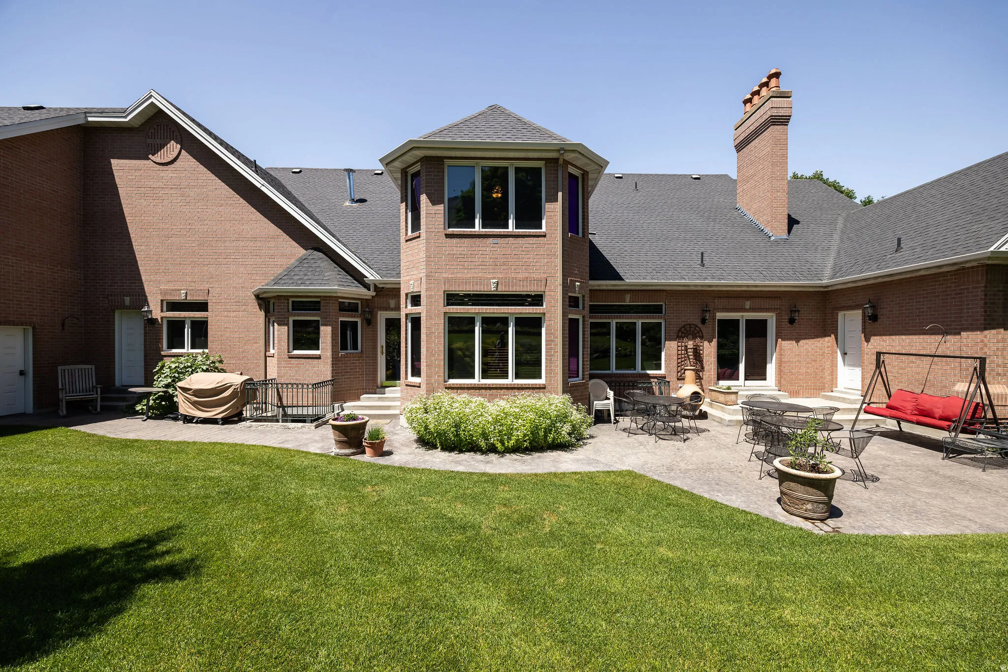 Brick exterior with a multi-level patio, a prominent brick chimney, and abundant fenestration