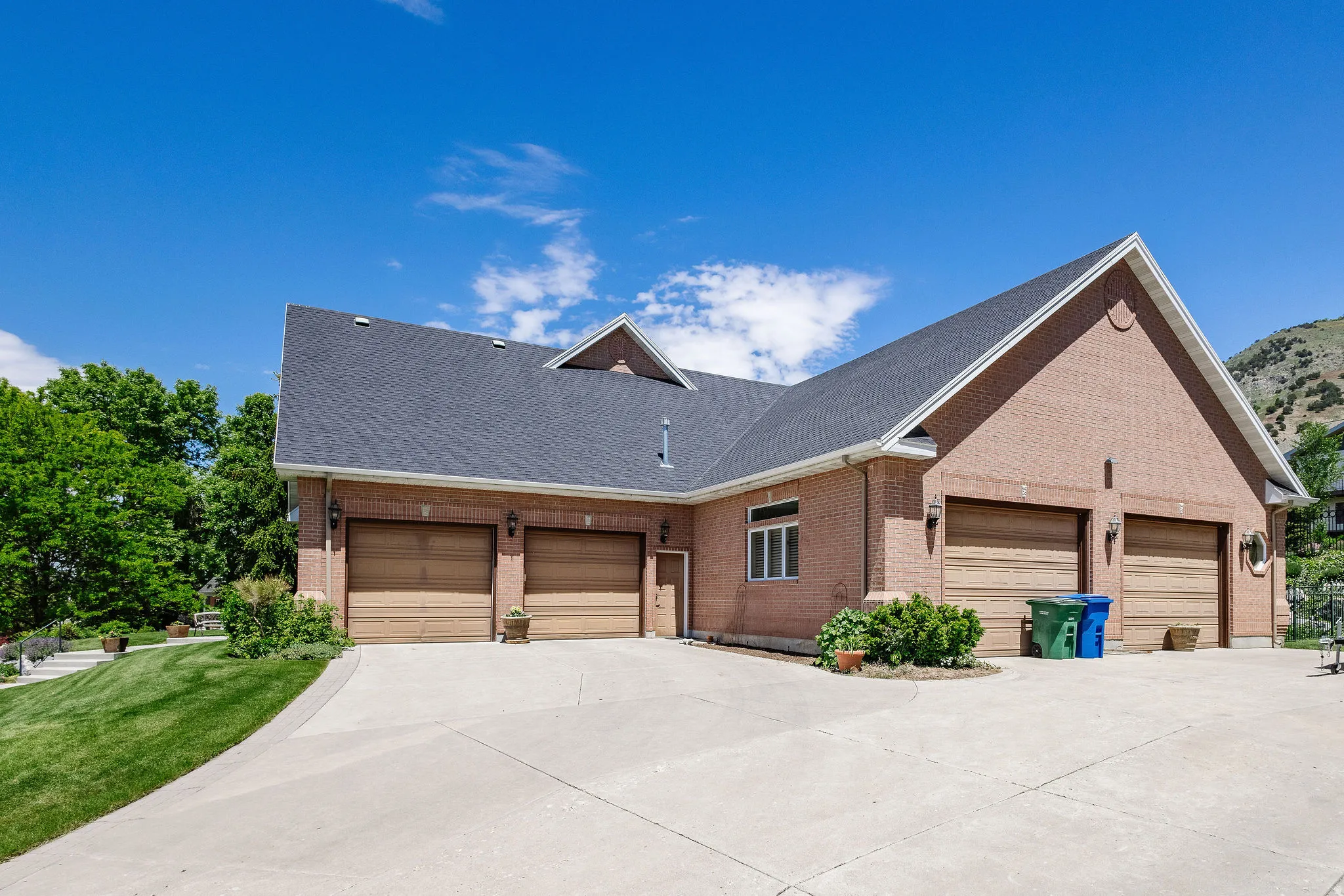 Brick exterior with a dark shingle roof, a multi-car garage with wood-finish doors, and a concrete driveway