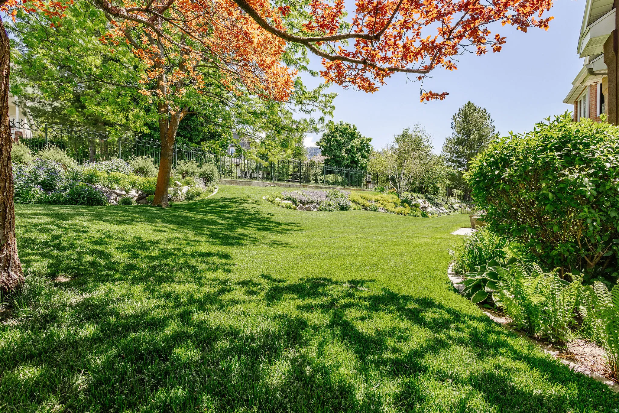 Expansive lawn area with mature trees and established landscaping beds
