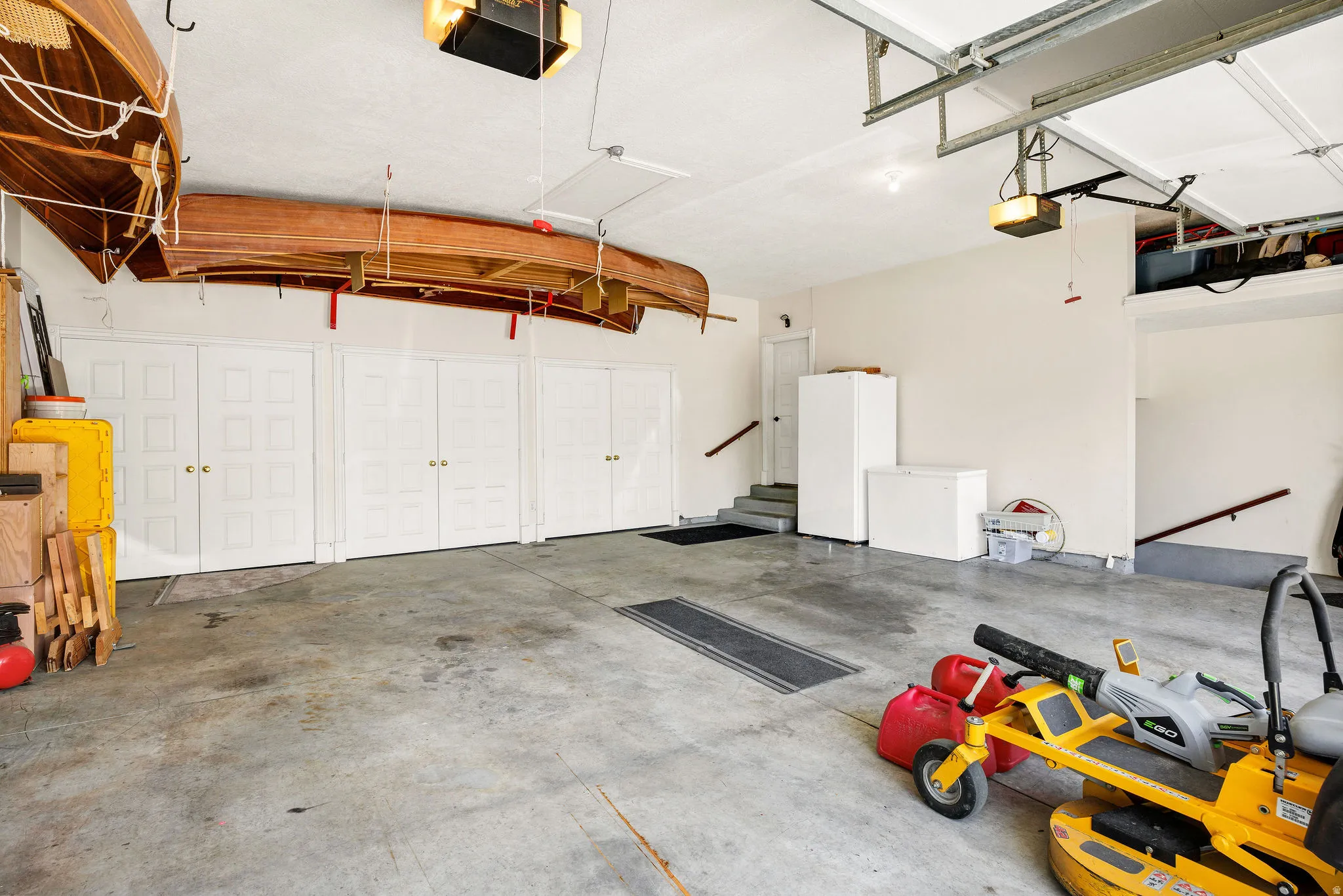 Attached garage with concrete flooring, multiple built-in storage cabinets, and stairs providing access to additional levels
