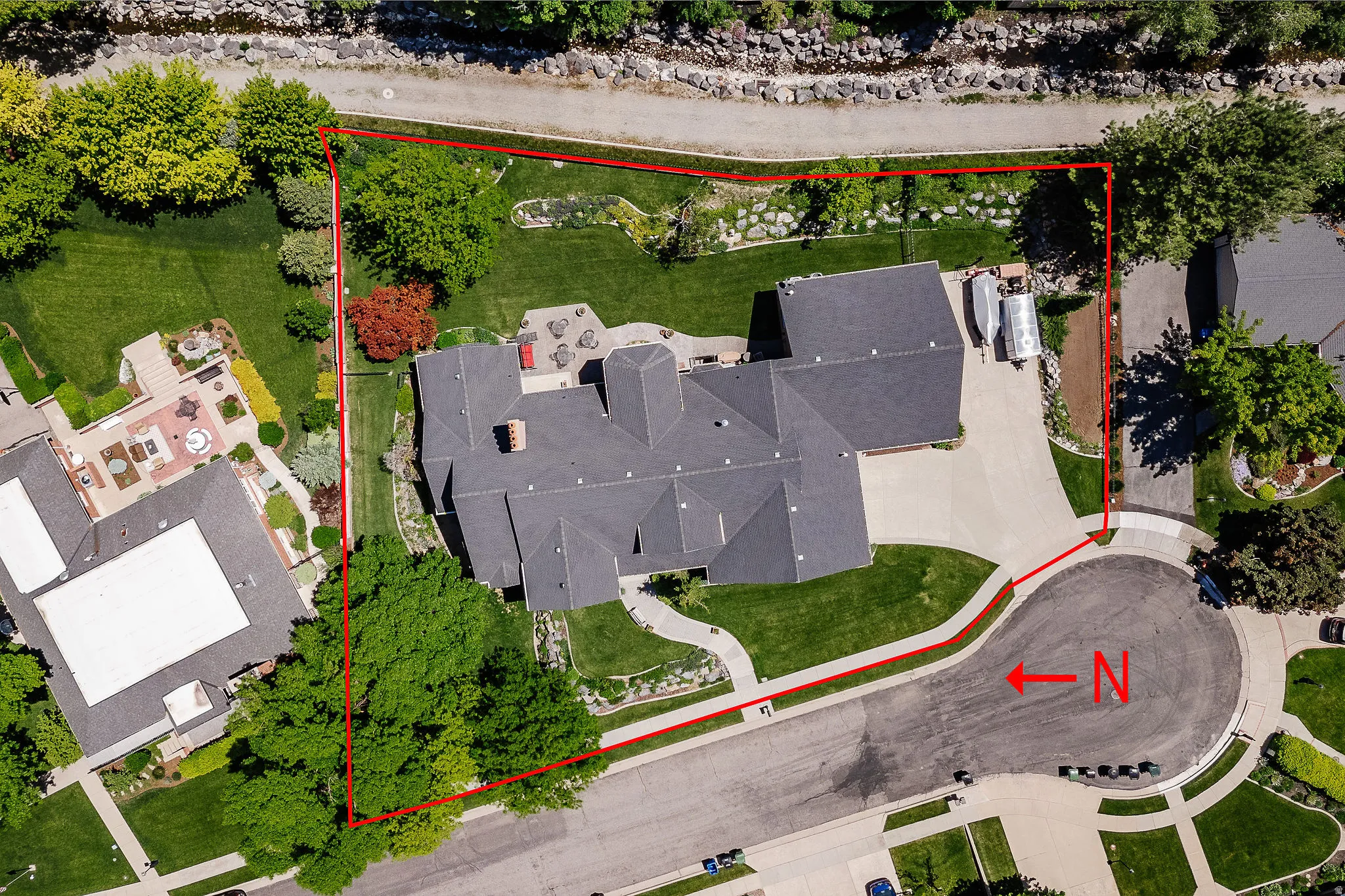 Expansive property with a multi-level structure, a dark shingle roof, and a paved driveway
